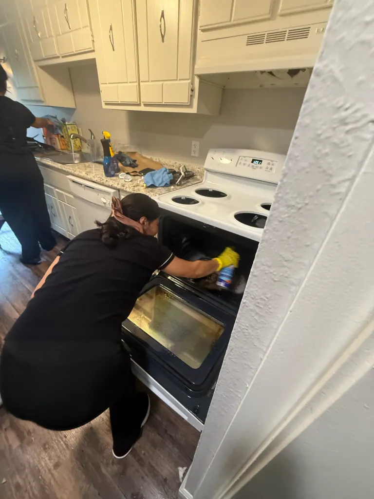 A Reina's Cleaning cleaner scrubbing the inside of an oven during a deep clean