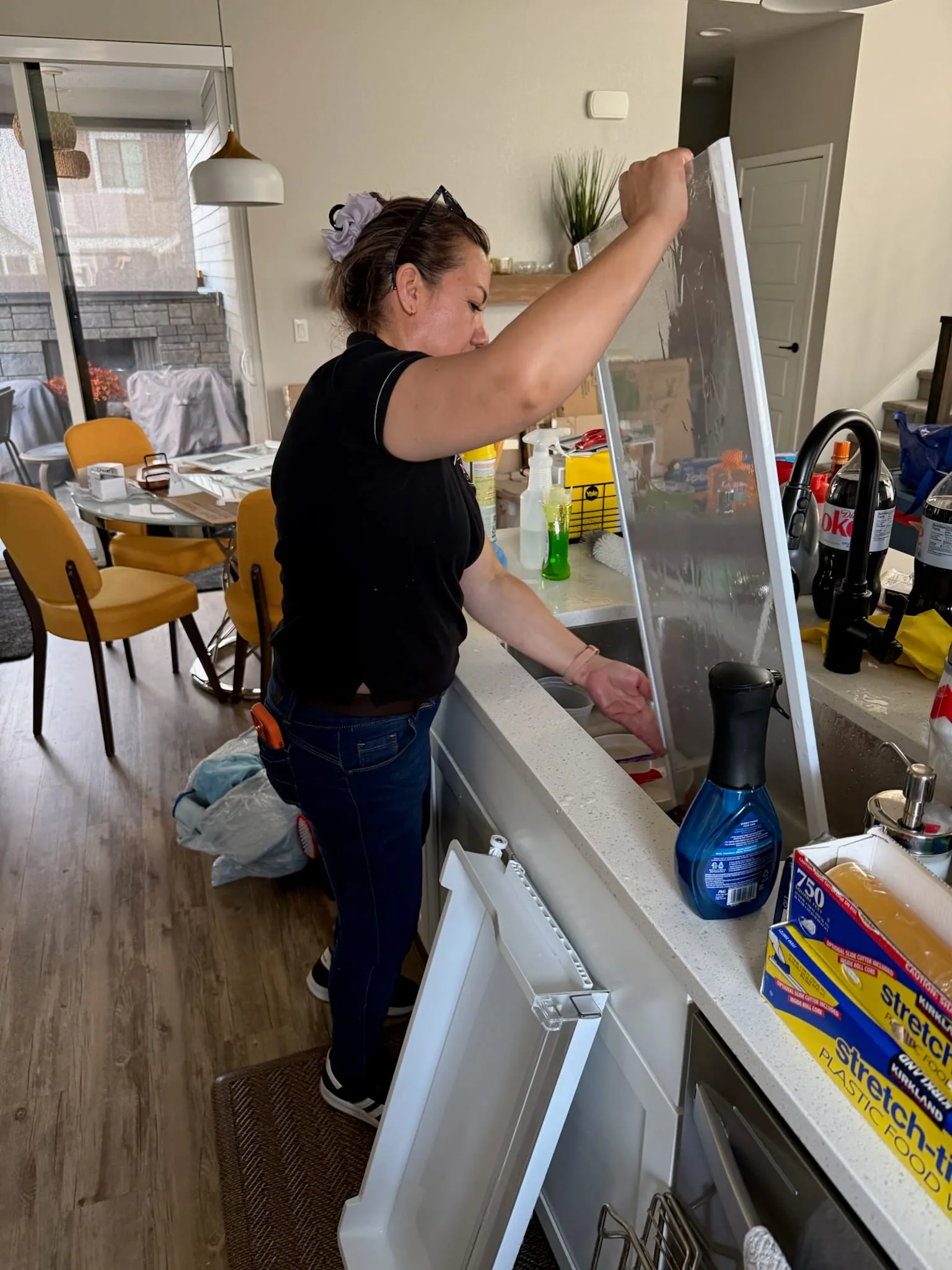 A Reina's Cleaning cleaner wiping the top of kitchen cabinets