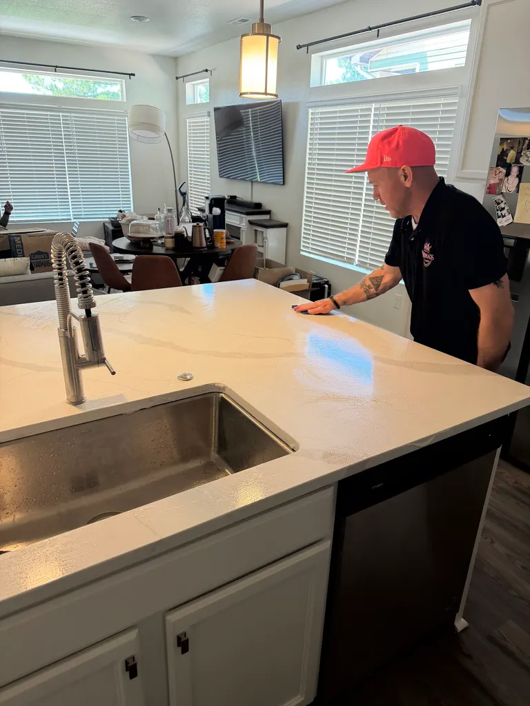 Josh from Reina's Cleaning wiping down a white quartz kitchen island